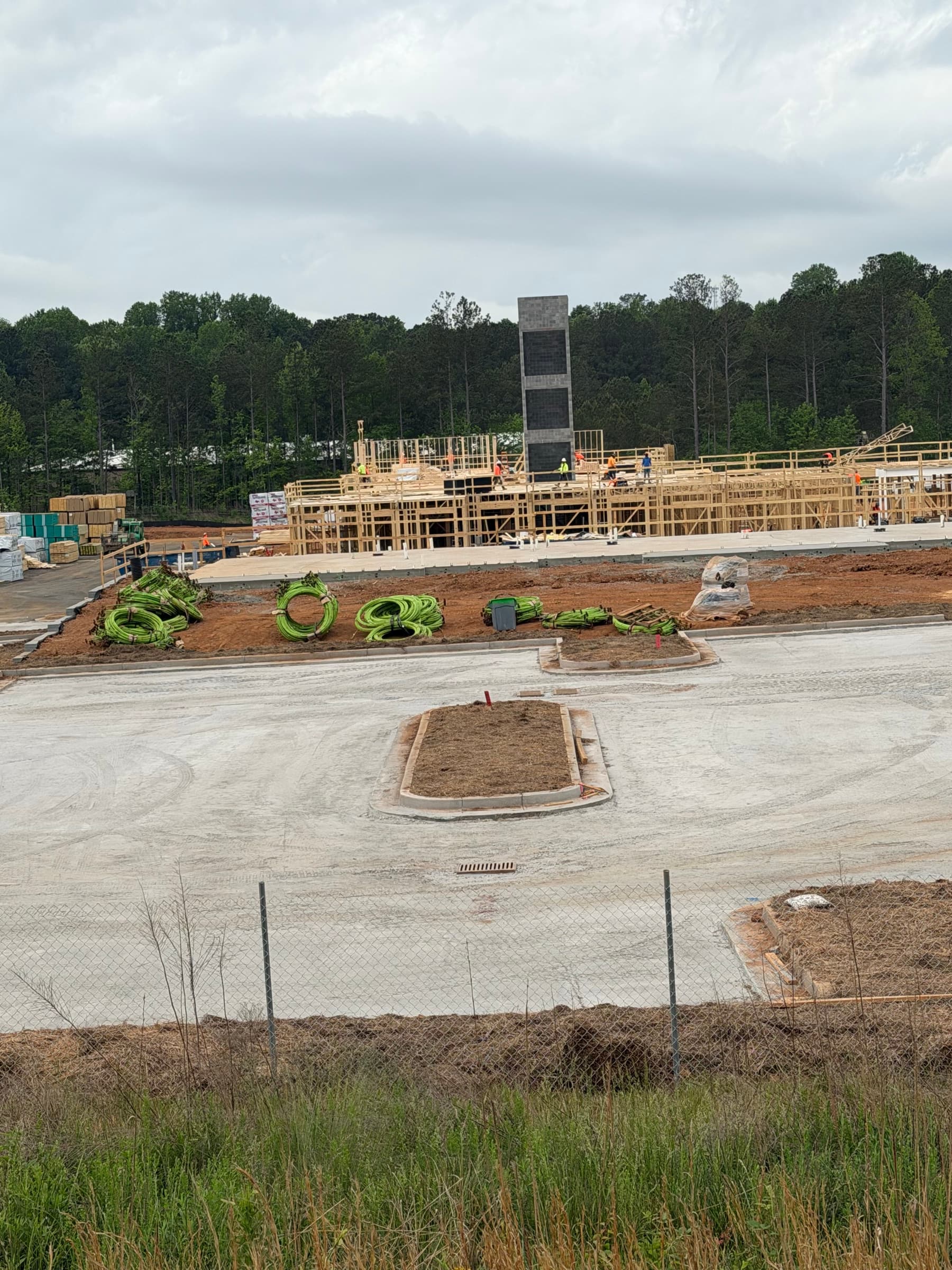 Drive-through building framing, utility coils, and concrete drives on an active Peachtree Corners commercial site.